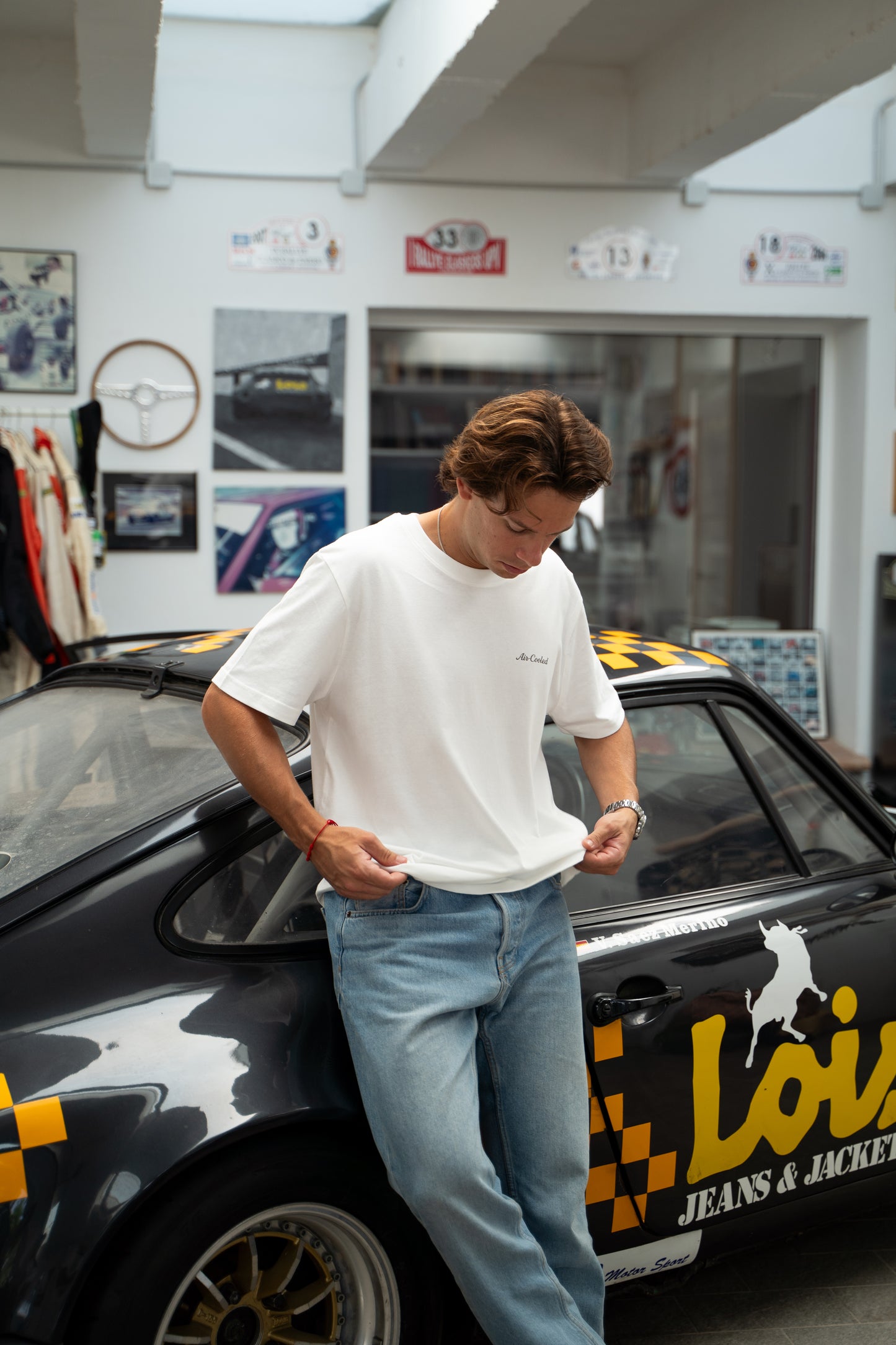 Person leaning against a car with visible branding in a garage setting