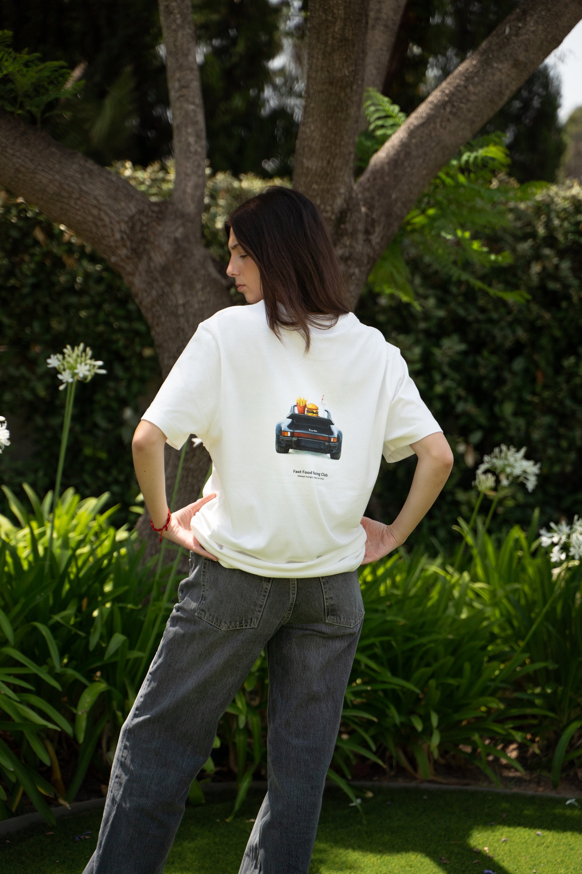 woman wearing a white t-shirt with a porsche 911 design outdoors