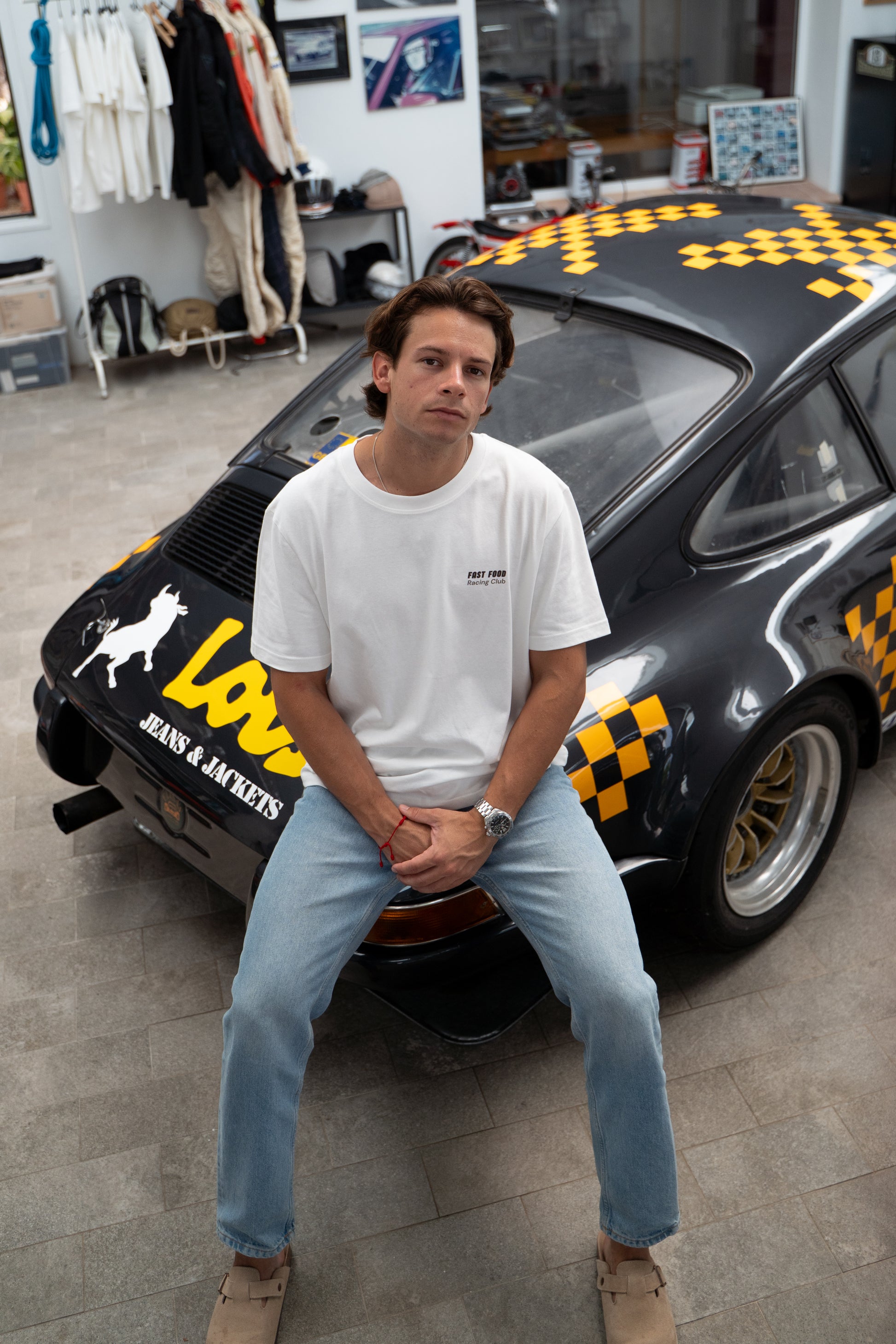 Man sitting in front of a porsche 911 racing car in a garage setting